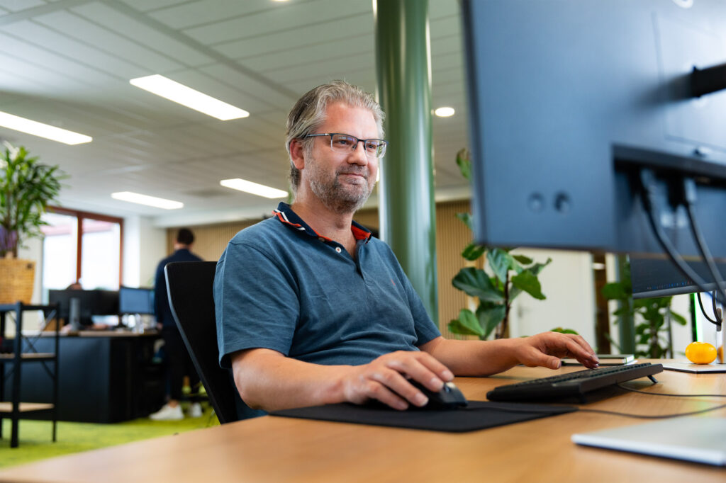 Lachende man werkend achter een computer