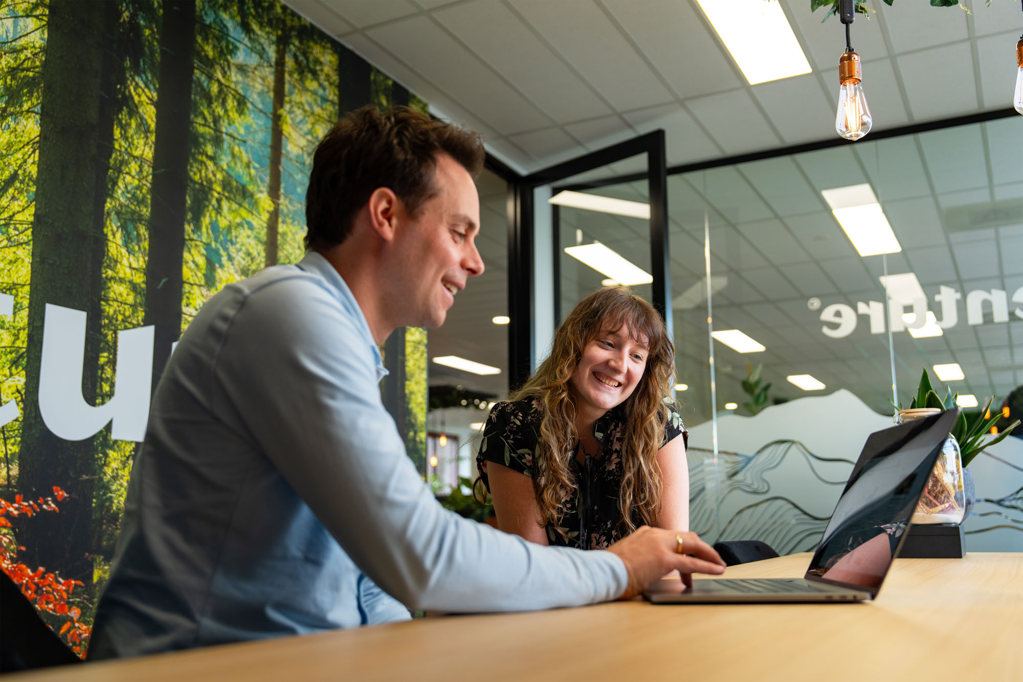 Man en vrouw lachend achter computer aan het werk