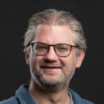 Lachende man met bril op zwarte achtergrond