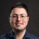 Lachende man met bril op voor zwarte achtergrond, portretfoto